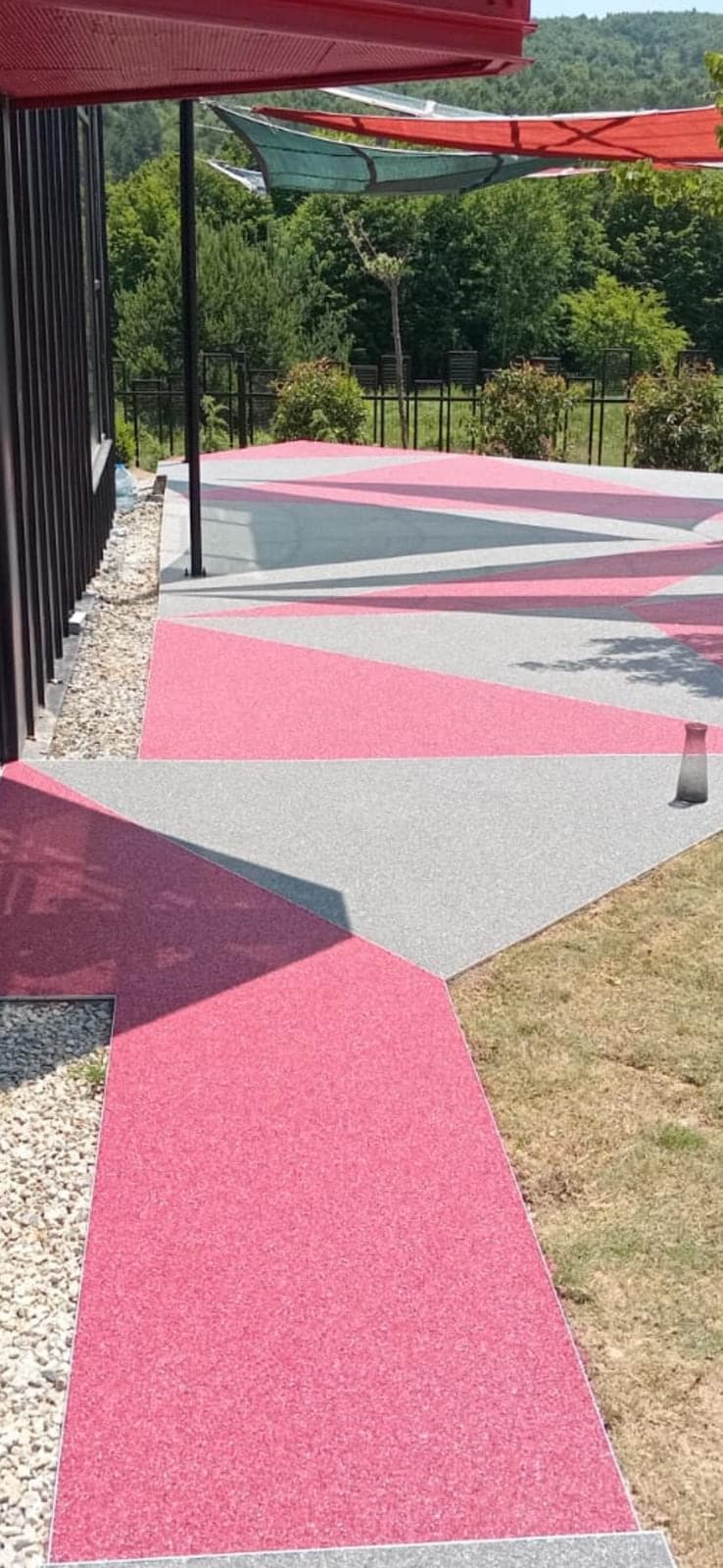 Dış mekânda pembe ve gri geometrik bölümlere ayrılmış taş halı zemin